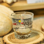 A cup of Soju on a coaster that's a slice of a small tree.