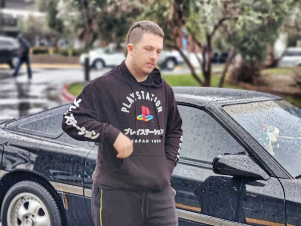 Harrison in a Japanese Playstation hoodie posing next to an MK3 Supra.