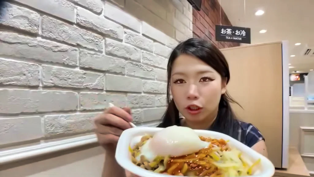 Hazunats holding up a bowl of 3 cheese gyudon with a poached egg on top from Sukiya.