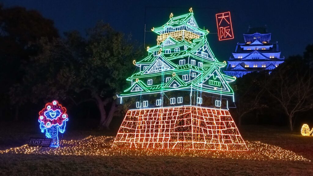 An illumination depicting Osaka Castle for Expo 2025 with the mascot and the actual Osaka castle in the background.